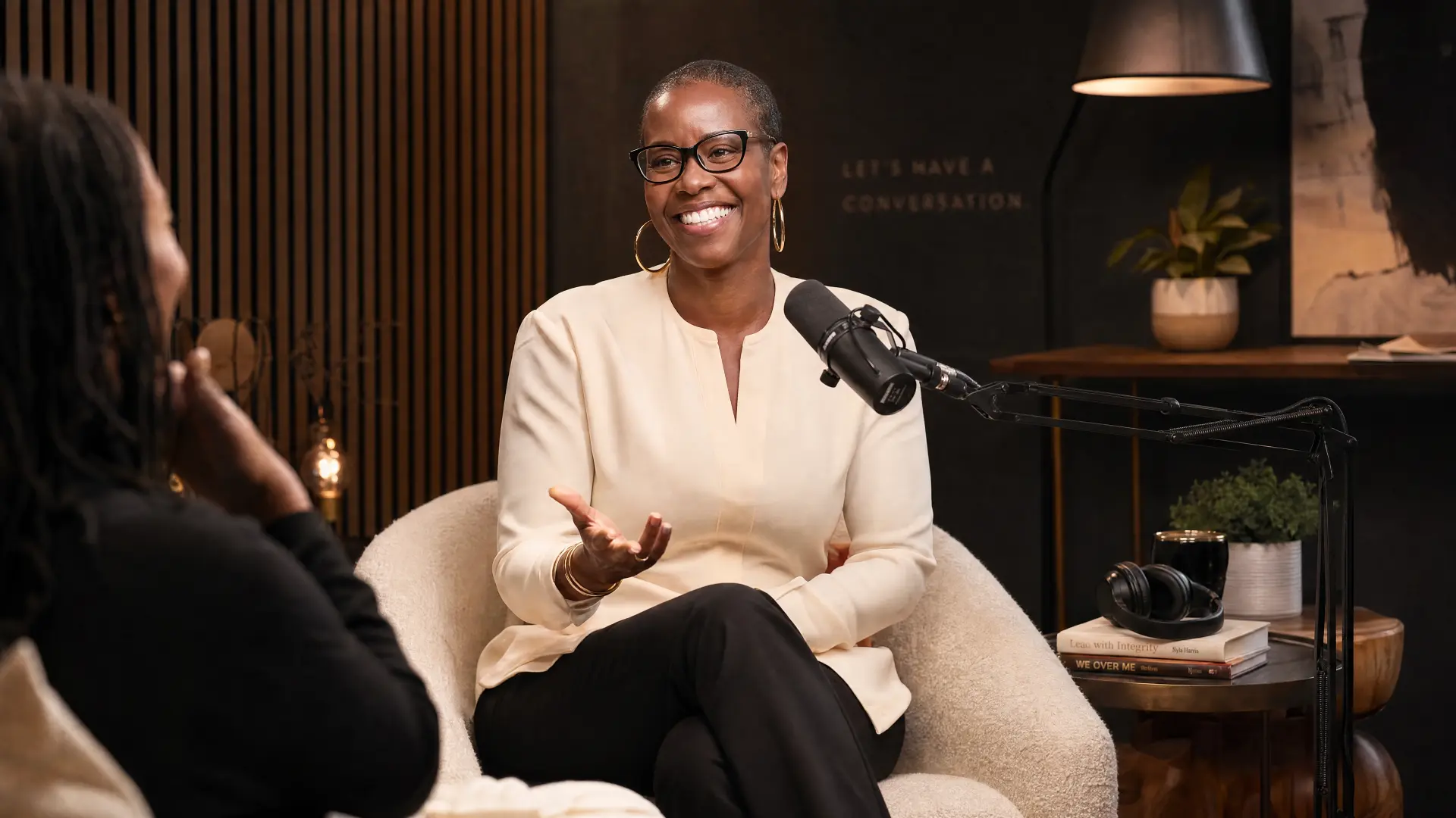 Nyia Harris in conversation, seated in a warm studio setting with a microphone