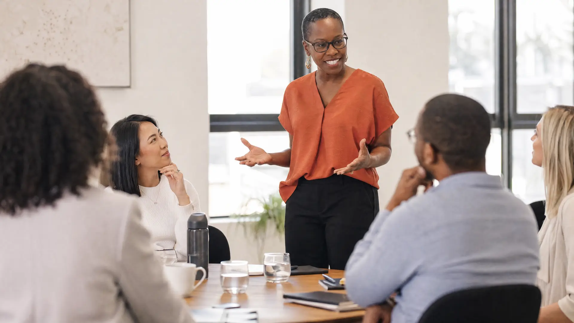 Nyia Harris standing and facilitating a conversation with a small group around a conference table